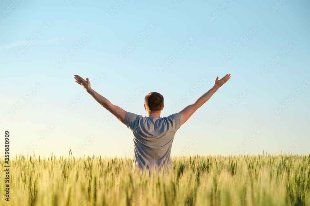 Adult man stands on a field in tall grass, arms spread out to the sides during sunrise. Digital detox, harmony with nature. Copy space. Adult man stands on a field in tall grass, arms spread out to the sides during sunrise. Digital detox, harmony with nature. Copy space.