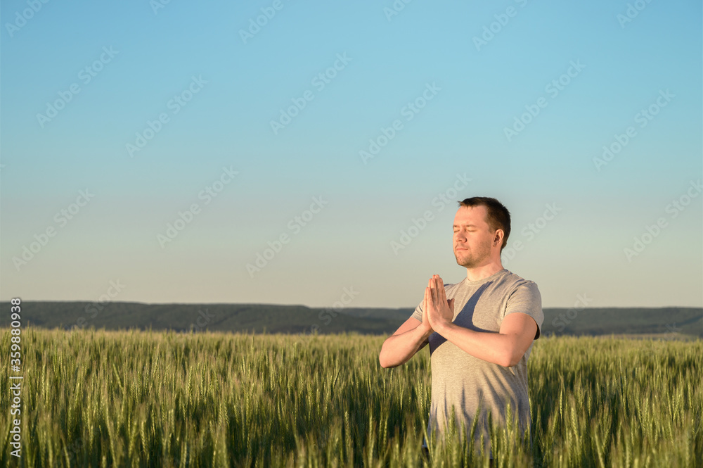 Adult man stands on a field in tall grass doing yoga during sunset. Digital detox, connection with nature concept. Copy space. Adult man stands on a field in tall grass doing yoga during sunset. Digital detox, connection with nature concept. Copy space.