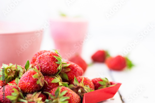 Fresh strawberry yogurt with berries around on a white wooden background. A pink shake in a glass  next to it is a pink cup with Hercules flakes  and red strawberries lie in a red star-shaped plate