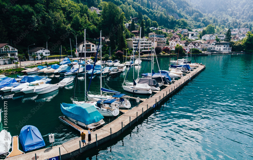 Aerial view of private motor boats moored in a small sea port surrounded by nature piedmont. Colorful fisherman's boats in dock harbour
