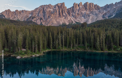 Picturesque peaks of Dolomites mountains in reflection of crystal clear pond surrounded by coniferous forest. Lake of Caresse in Italy. Scenic place and famous touristic destination. Primeval nature © BullRun
