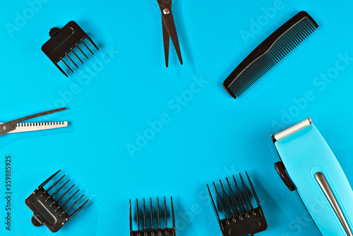 Haircut accessories on a blue background. Haircut machine with different attachments and scissors. Layout for design. Copy space and space for text near tools. photo