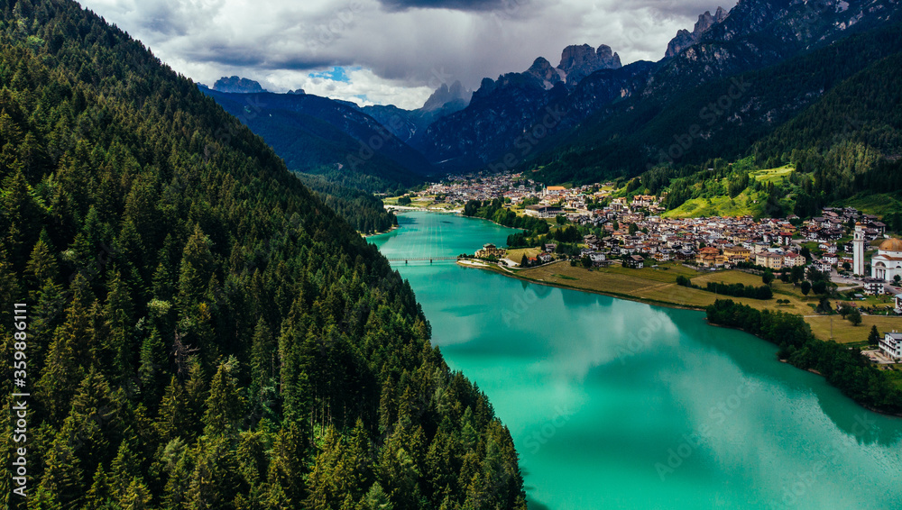 Aerial view of picturesque land in the valley of the Dolomites Alps, small town located near the turquoise river at foot of the majestic mountains. Scenic village in Natural Park