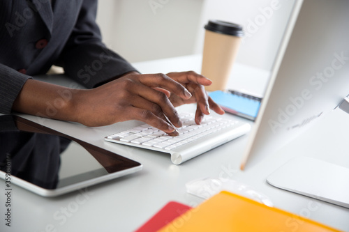 Close-up of hands of african-american businesswoman typing on a laptop.