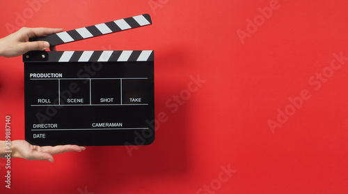 A Hand is holding Black clapper board or movie slate on red background.It used in cinema industry and video production.