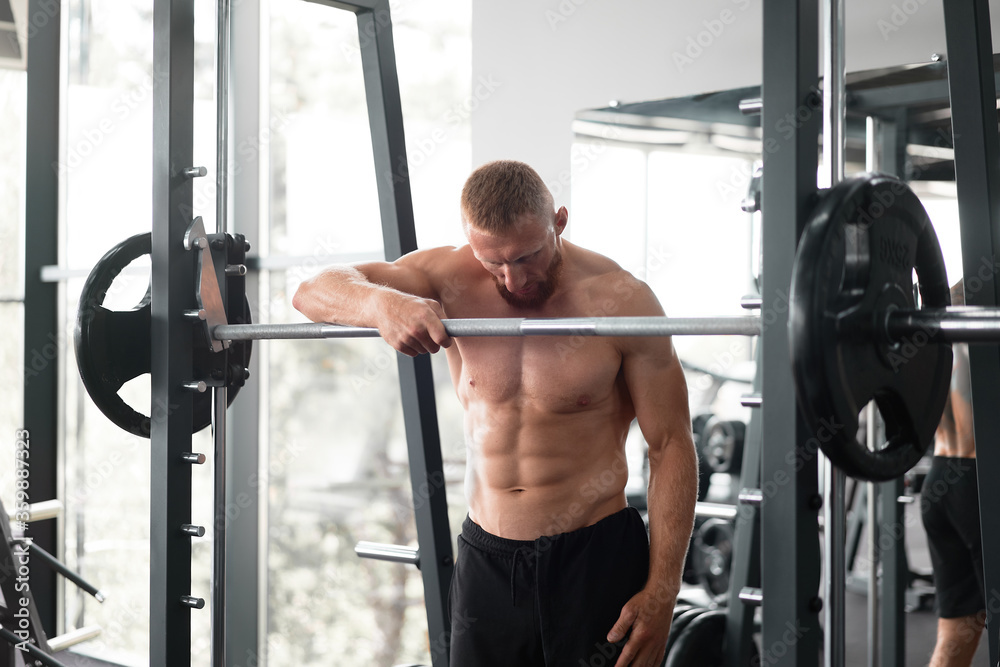 Gym man leaning barbell resting after hard training. Handsome caucasian athlete take break. Gym man leaning barbell resting after hard training. Handsome caucasian athlete take break.