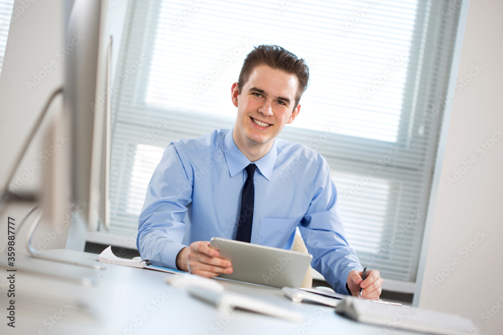 Portrait of young businessman working with tablet computer at office