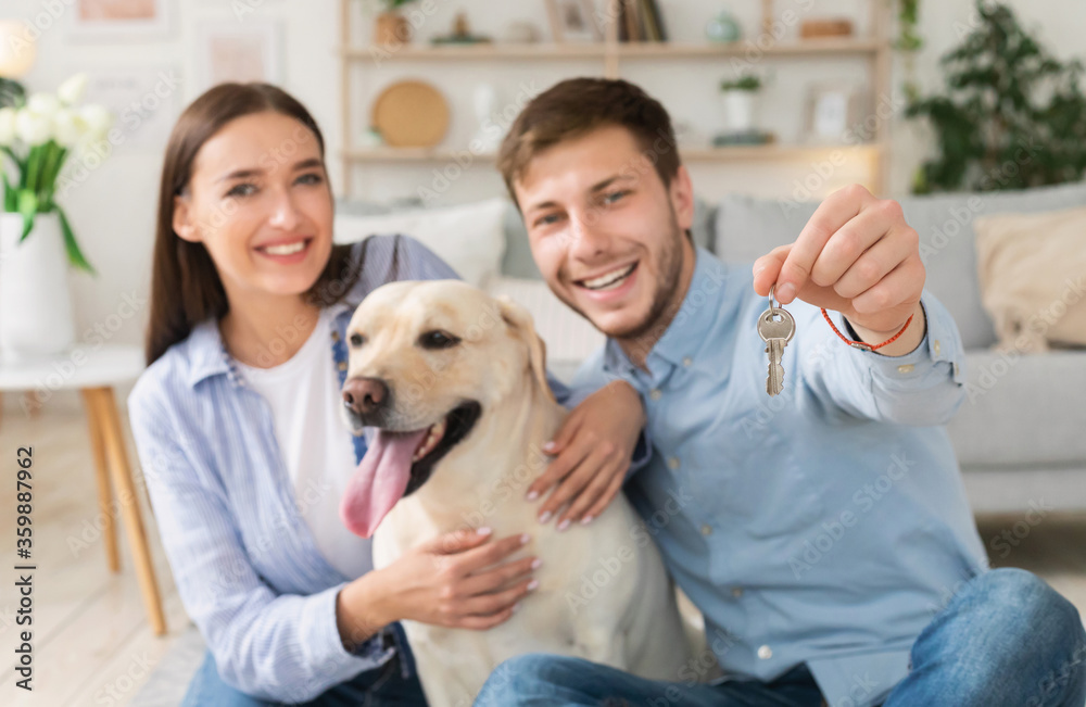 Young happy couple with dog showing keys from new home