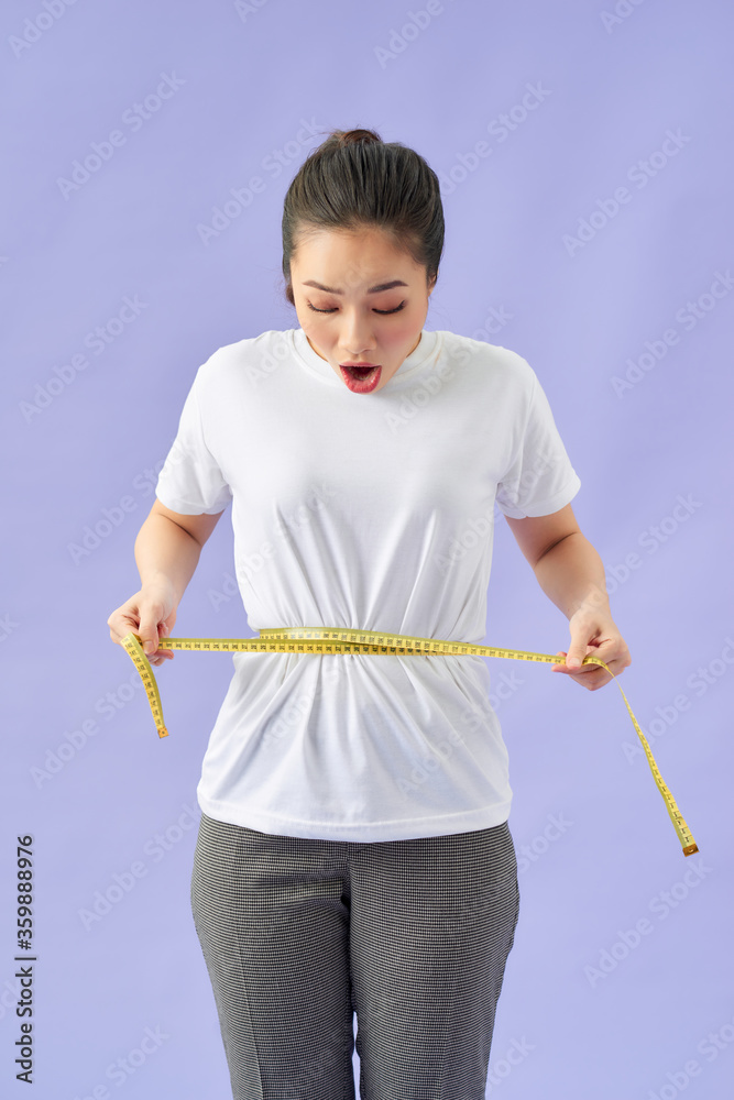 young woman measuring waist with measuring tape young woman measuring waist with measuring tape