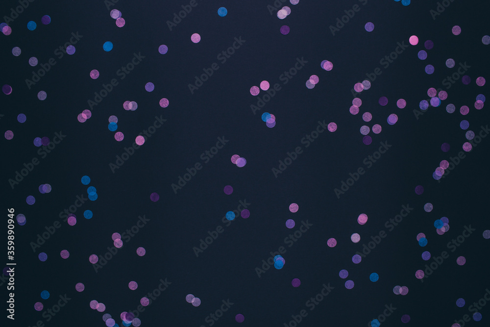 Dark background with pink and blue round confetti. Festive background for your design. Flat lay, copy space, top view.