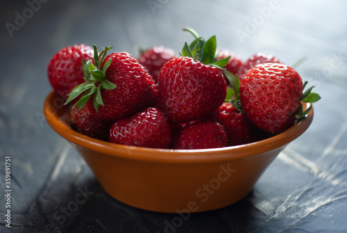 strawberries in a ceramic bowl on a concrete table 