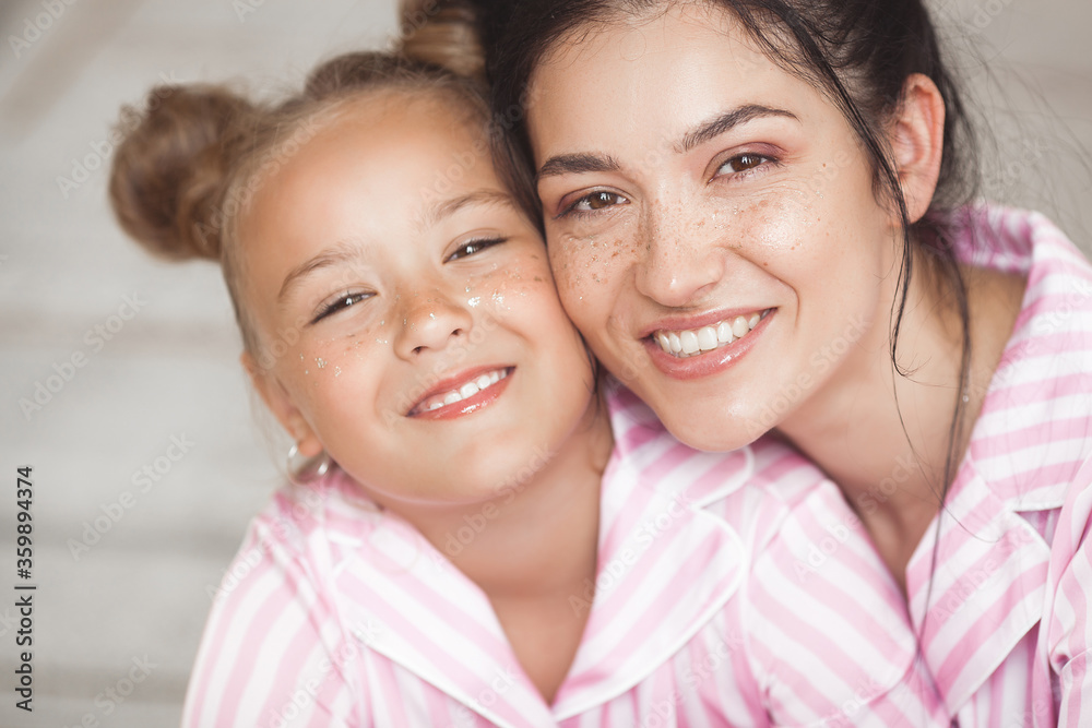 Young attractive mother and her little daughter having fun at pajamas party. Family in the morning Young attractive mother and her little daughter having fun at pajamas party. Family in the morning