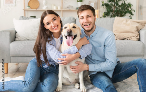 Young happy spouses with dog sitting in living room