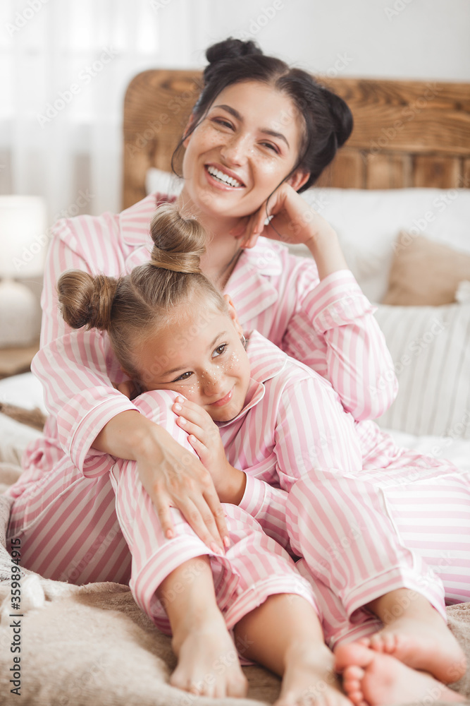 Young attractive mother and her little daughter having fun at pajamas party. Family in the morning Young attractive mother and her little daughter having fun at pajamas party. Family in the morning