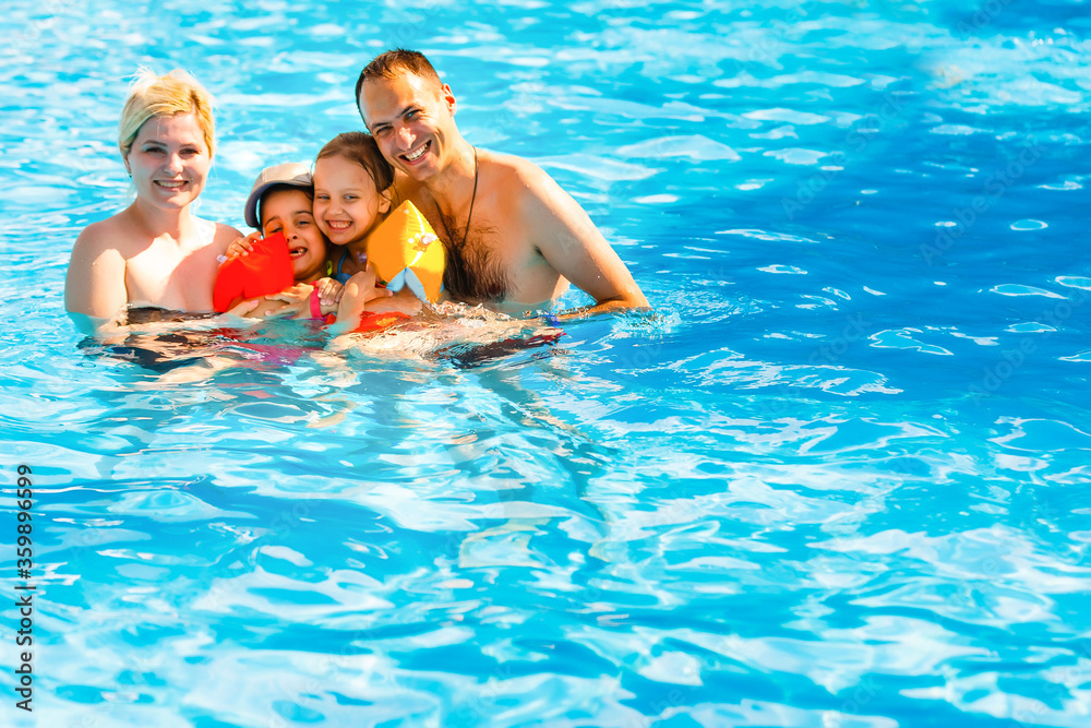 Young family, parents with children, in pool