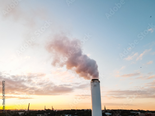 Environment pollution concept: Large white pipe emits a lot of smoke causing greenhouse effect in the centre of city