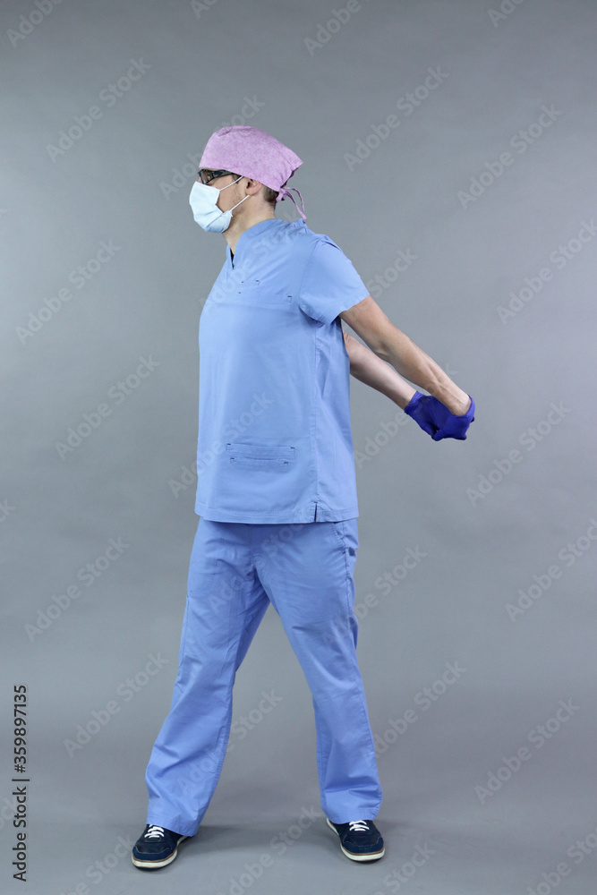 Exercise for medic, nurse,  dentist in standing position.Caucasian man in uniform, mask and eyeglasses , stretching body  - healthy lifestyle at work