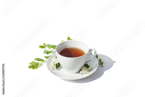 White tea mug with a dessert plate and fresh white flowers on white background