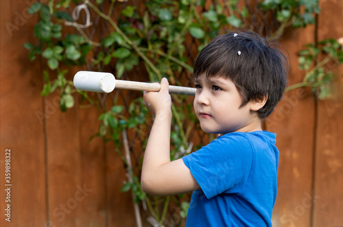 Portrait active young boy playing with wooden hammer toys in the garden, Positive child boy playin goutdoor in sunny day spring or summer. photo