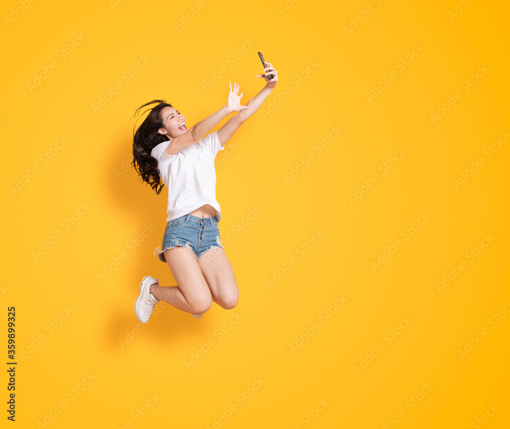young woman jumping while taking selfie by mobile phone young woman jumping while taking selfie by mobile phone