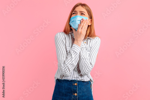 beautiful young woman in a medical protective mask on her face, suffering from severe toothache, touching her cheek with her hand. Toothache