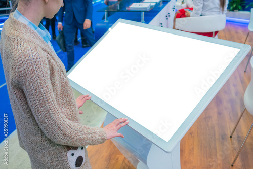 White screen, mockup, science, copyspace, template, isolated, technology concept. Woman looking at blank white display of interactive kiosk at exhibition or museum with futuristic sci-fi interior photo