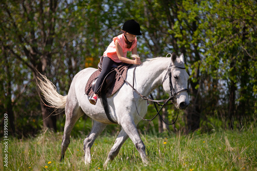 Little girl rides a white horse breed Orlov trotter © evannovostro