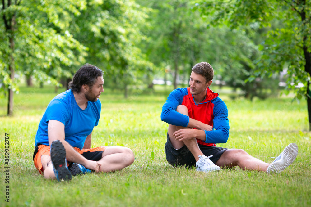 Two friends taking rest after workout in public park.