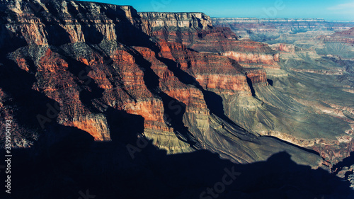 Aerial view of Grand Canyon National Park with antique Colorado Plateau geological rocks and cliffs over abysses, bird's eye view of beautiful scenery in famous touristic sight viewpoint with blue sky