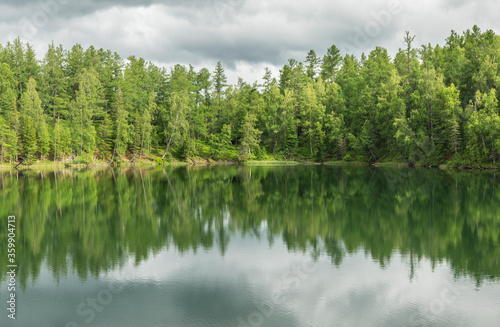 Wild forest lake. Gloomy sky  beautiful reflection. Travel and summer vacation.