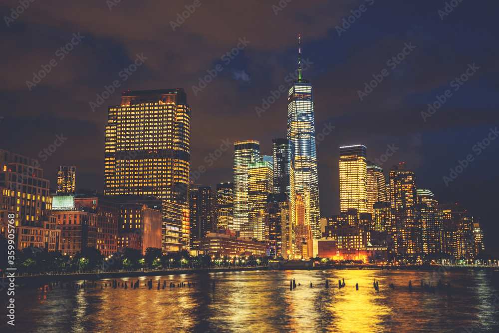 Scenery view of Lower Manhattan skyline at night with city lights reflected in Hudson river. Beautiful New York cityscape view. Contemporary metropolis city in need of a huge amount of electricity
