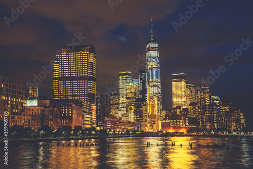 Scenery view of Lower Manhattan skyline at night with city lights reflected in Hudson river. Beautiful New York cityscape view. Contemporary metropolis city in need of a huge amount of electricity