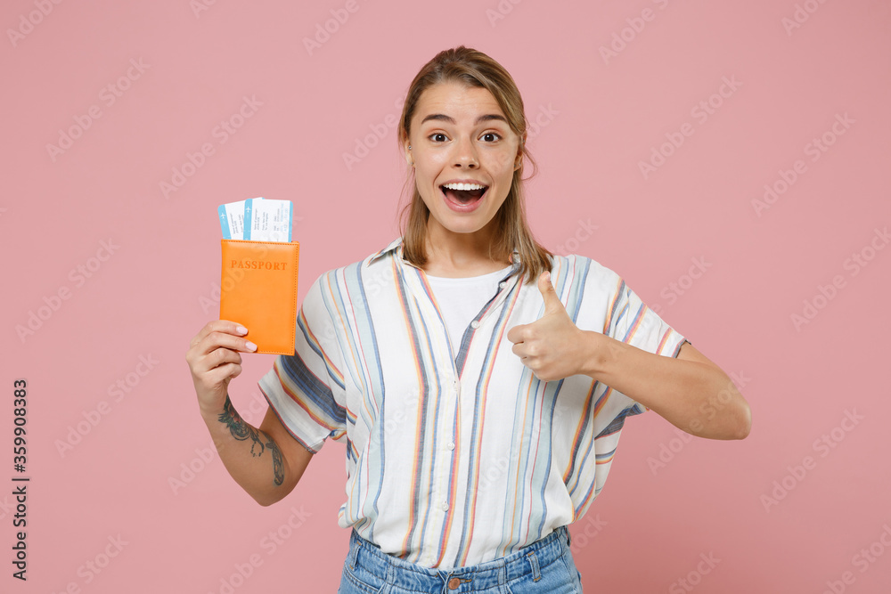 Excited young woman girl in striped shirt isolated on pink wall background. Passenger traveling abroad to travel on weekends getaway. Air flight journey concept. Hold passport ticket showing thumb up. Excited young woman girl in striped shirt isolated on pink wall background. Passenger traveling abroad to travel on weekends getaway. Air flight journey concept. Hold passport ticket showing thumb up.