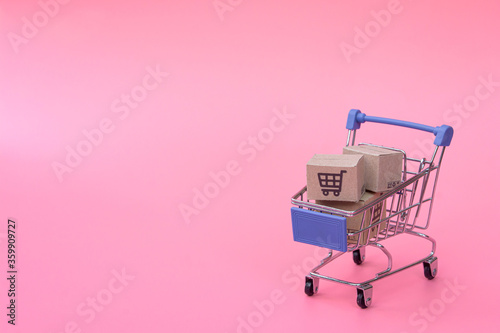 Shopping concept : Cartons or Paper boxes in blue shopping cart on pink background. online shopping consumers can shop from home and delivery service. with copy space.