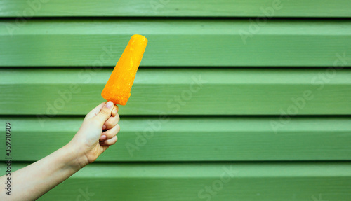 Ice cream in hand, yellow fruit ice hot summer concept photo