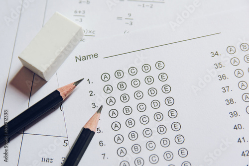 Pencil and eraser on answer sheets or Standardized test form with answers bubbled. multiple choice answer sheet