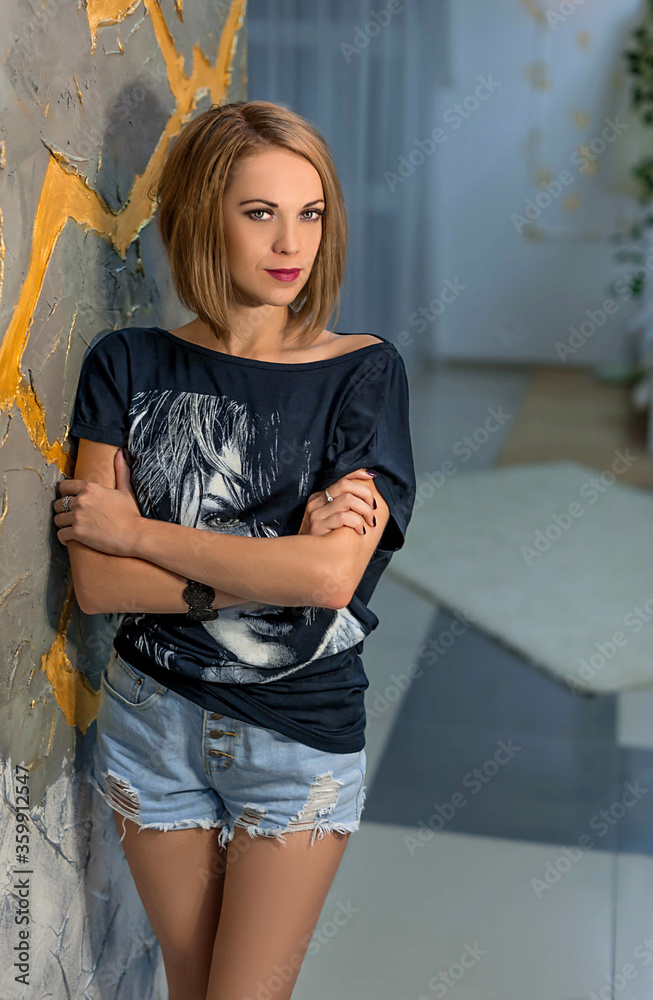 Fototapeta premium slim girl in shorts and a t-shirt with a suitcase. Mysterious traveler
