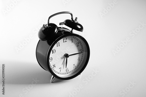 Black vintage alarm clock on table. White background. Wake up concept. An image of a retro clock showing 06:16 pm/am. 