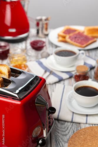 Close up photo of kitchen table with .appliances, kitchenware with toasts and jams