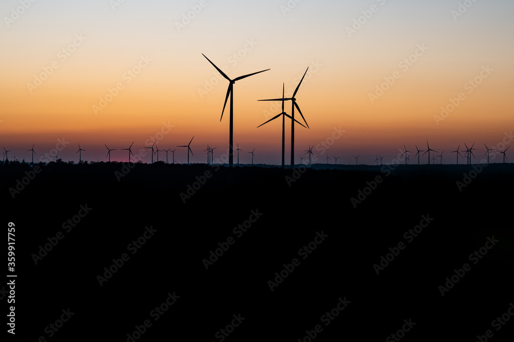 Fototapeta premium Czarna sylwetka generatora energii turbiny wiatrowej na niesamowity zachód słońca na farmie wiatrowej w Niemczech