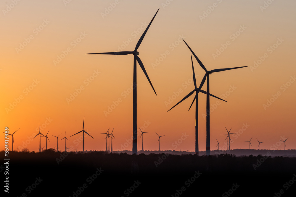 Black Silhouette of windturbines energy generator on amazing sunset at a wind farm in germany
