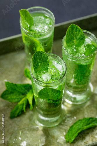 Summer Sweet Refreshing Mint Liqueur Cocktail Shots with Ice and Mint Leaves on Tray, Close View. Selective focus.
