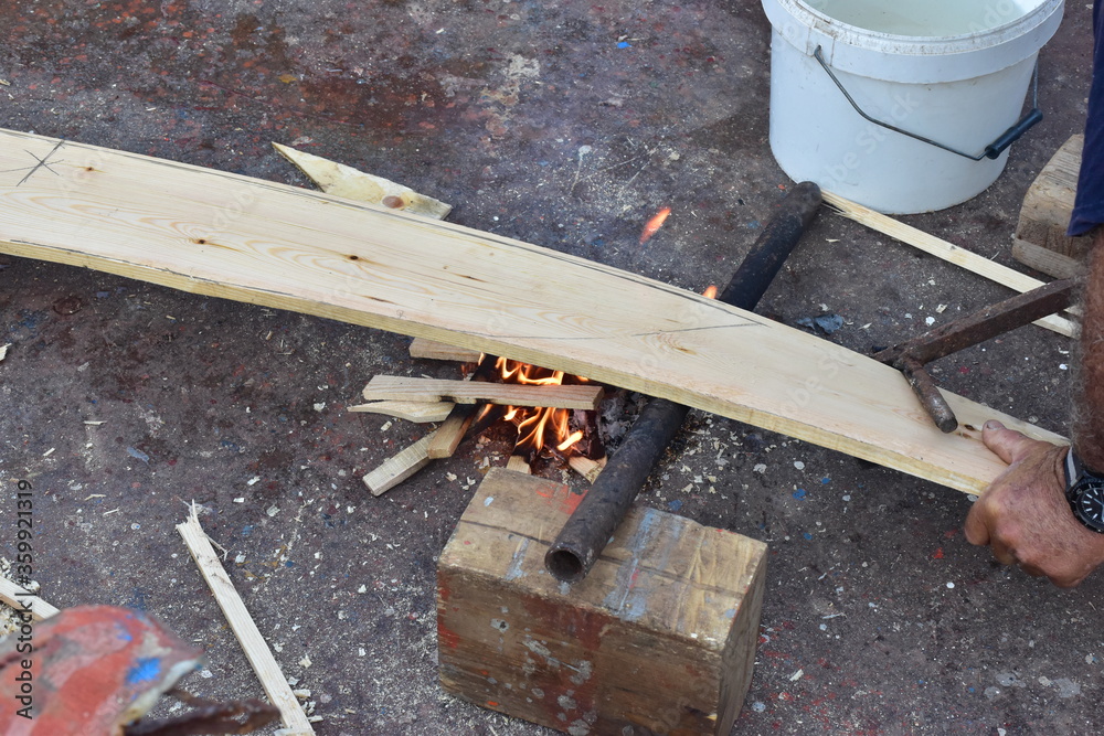 lavorazione tradizionale del fasciame di una barca in legno, piegamento a fuoco delle tavole in legno. Sicilia