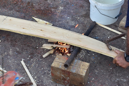 Obraz na płótnie lavorazione tradizionale del fasciame di una barca in legno, piegamento a fuoco delle tavole in legno. Sicilia w salonie