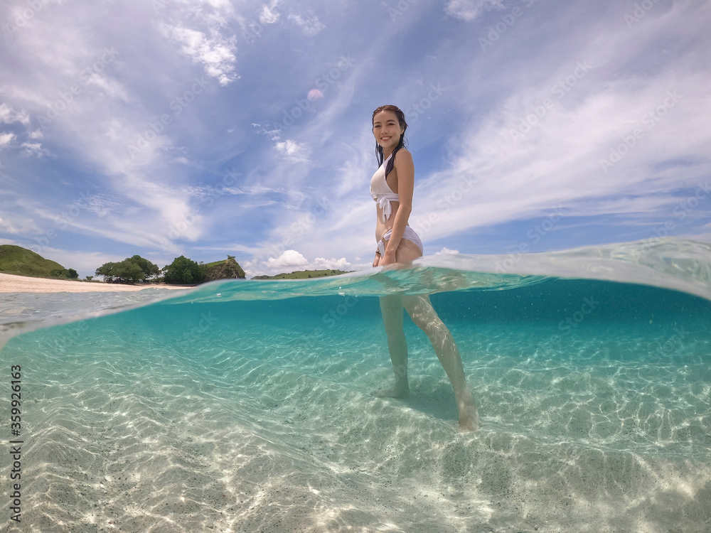 Half water view of woman in white bikini standing. pink sand at Komodo island, Indonesia.