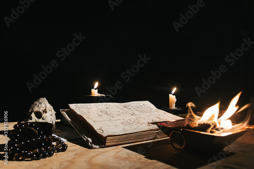 Occult white magic ritual of fire using grimoire, old book, candles