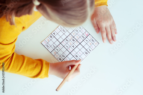 Teen girl solving sudoku at school or at home. View from above