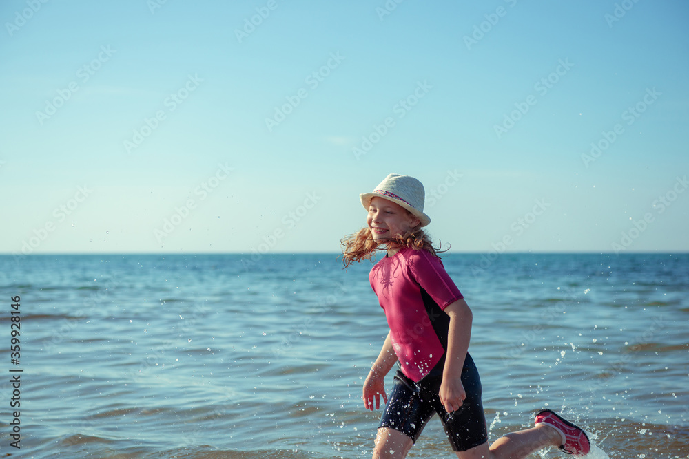 Happy pretty teen girl in neoprene swimingsuit running in Baltic sea Happy pretty teen girl in neoprene swimingsuit running in Baltic sea
