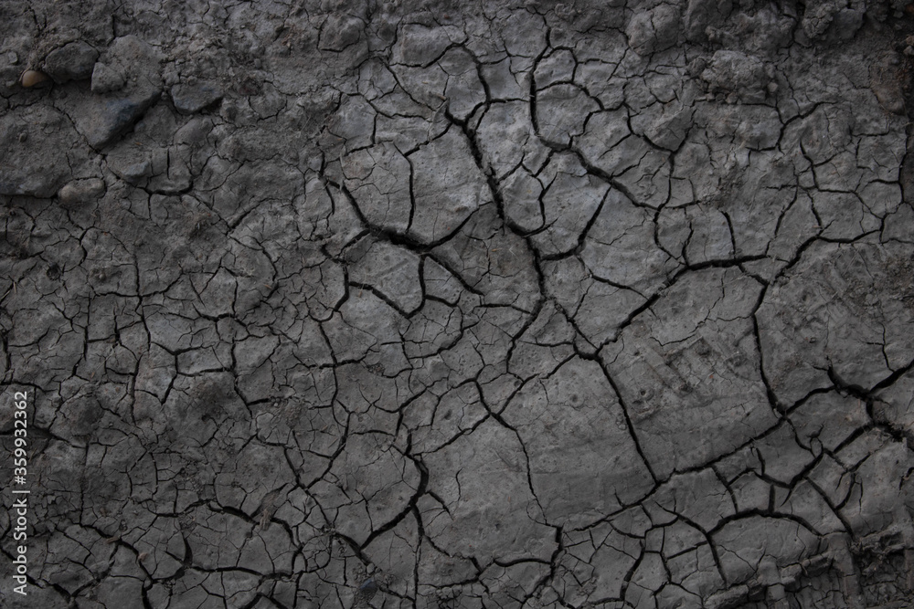 Fototapeta Cracks in the ground due to drought.The concept of global warming. A desolate landscape cracked by drought