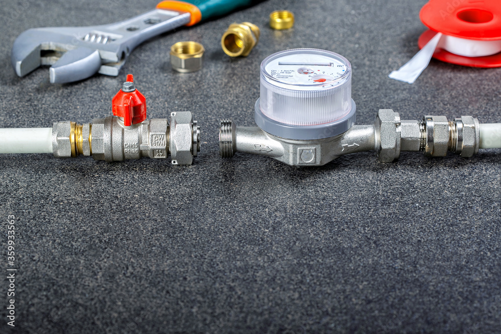 Installing water meter. Various water system accessories and wrench on gray surface with copy space. Installing water meter. Various water system accessories and wrench on gray surface with copy space.